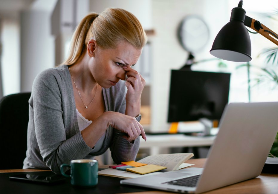 woman with a headache looking at her computer