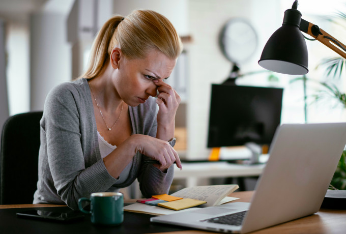 woman with a headache looking at her computer